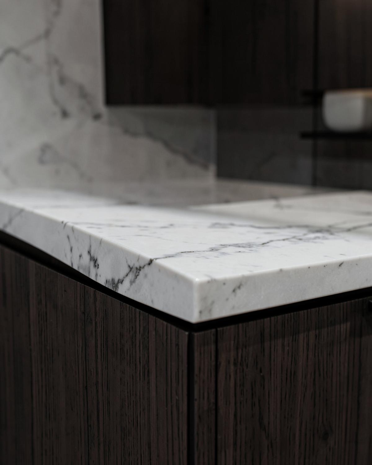 Marble countertop edge meeting dark wood cabinetry